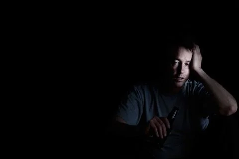Mature man displaying depression while drinking on dark background Stock Photos