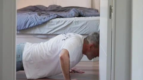 Mature man doing push-ups at home in the bedroom Stock Footage 341582940