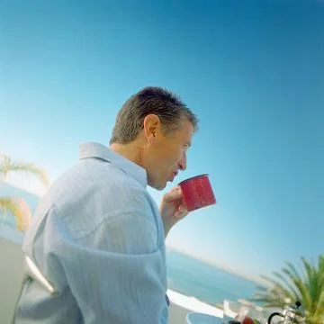 Mature man drinking from mug, side view Foto stock