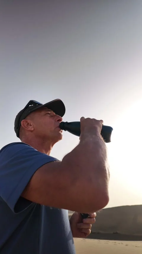 Mature man drinking water from a reusable bottle in the desert Stock Footage 345093184
