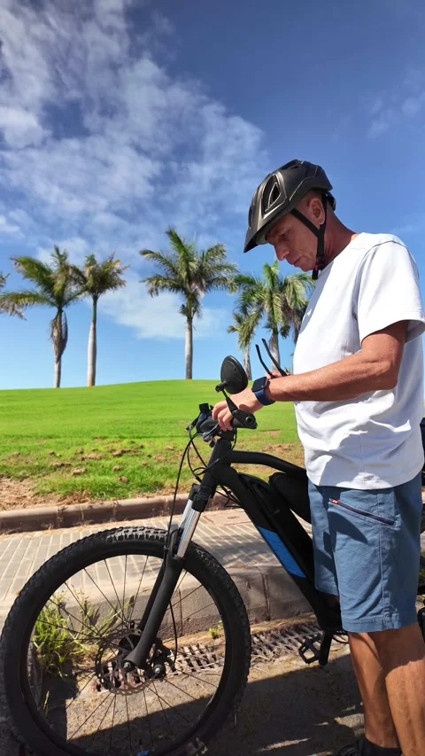 Mature man with e-bike checking his smartwatch Stock Footage 344816351