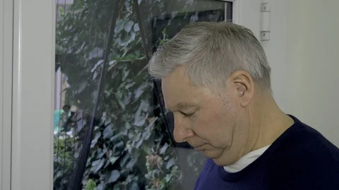 Mature man expresses worry while looking out of the window	 Stock Footage 97159535
