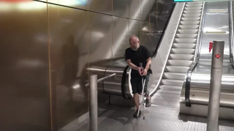 Mature man goes down the escalator to the subway using crutches Stock-Footage 281726616