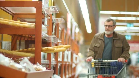 Mature man with a gray beard and glasses rides with a trolley through a Stock Footage 101354454