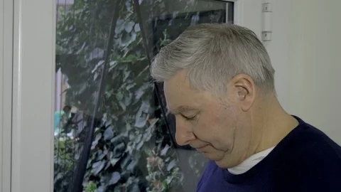 Mature man looking down then looks up to face the camera frowning Stock Footage 97160105