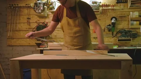 A mature man makes a marking on a board that he has sanded with a grinding ma Video stock 182227216