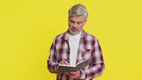 Mature man making notes writing thoughts with pen into notepad notebook diary to Stock Footage 314586285