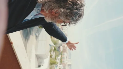 Mature man making video call from mobile phone while standing on balcony Vídeo Stock 229507677