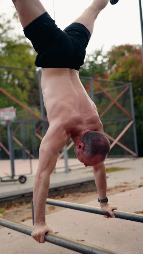 Mature Man Performing Handstand on Parallel Bars in a Park Stock-Footage 313501492