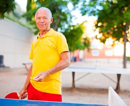 Mature man posing with rackets at table tennis Foto stock
