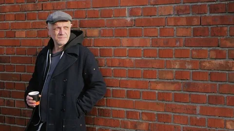 Mature man posing at red brick wall, holding a coffee Stock-Footage 82873368