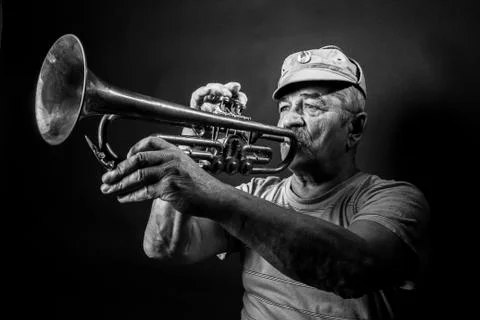 Mature man posing with trombone in front of portrait backdrop Stock Photos