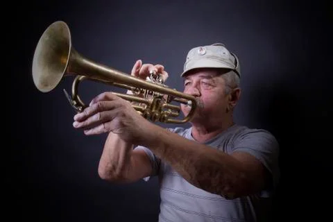 Mature man posing with trombone in front of portrait backdrop Stock Photos
