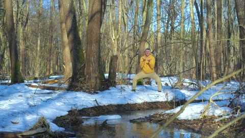 Mature man practicing breathing exercise beside stream in spring forest Stock Footage 335194530