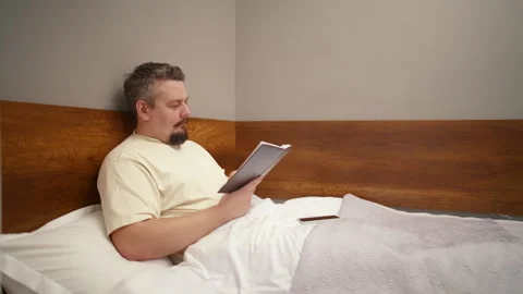 Mature man reading a book in bed before sleeping 库存影片 340931679