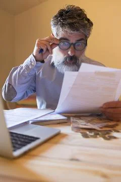 Mature man realizing financial problems reviewing bills at home 스톡 사진