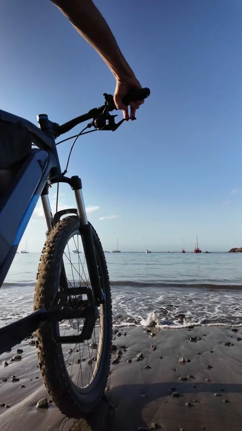 Mature man riding an e-bike on a sandy beach Stock Footage 344816242