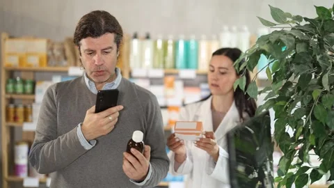 Mature man scans the barcode of cough syrup on mobile to pay for the goods in an Stock Footage 317991986