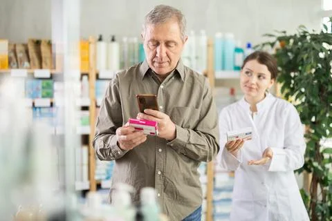 Mature man scans QR code on box pills label. Female pharmacist offers to choose Stock-Fotos