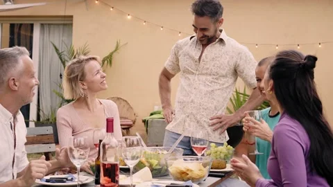 Mature man serving the table to his friends at an outdoor gathering in the Stock Footage 239106433