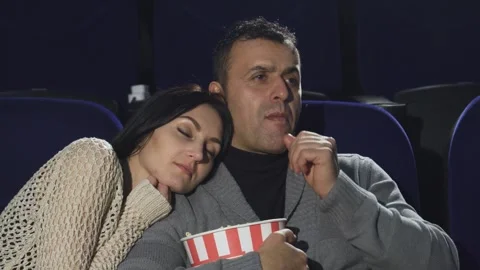 Mature man shushing to the camera while watching a movie with his wife Stock Footage 311939751