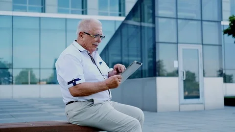 Mature man with tablet sits on bench at modern office center Stock Footage 115884126