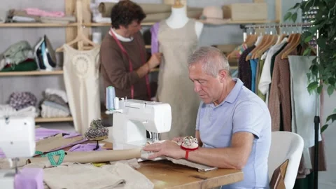 Mature man tailor at work, other man work with mannequin in background Stock Footage 329540842