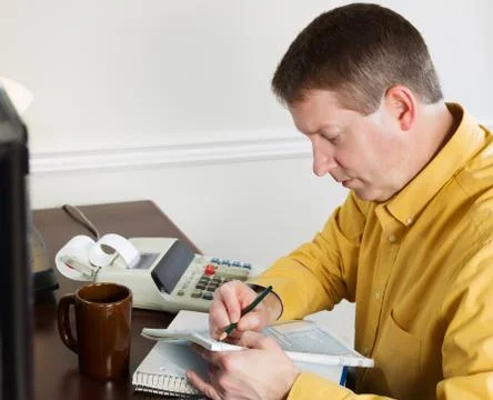 Mature man taking data off the computer for doing income taxes Foto stock