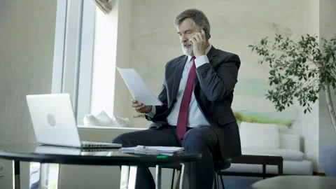 Mature man talking smartphone at remote workplace or office Video stock 252360716