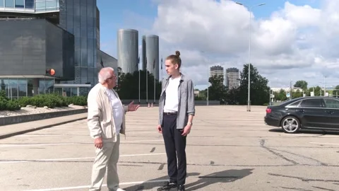 Mature man talks to young guy walking along parking site Stock Footage 139797815