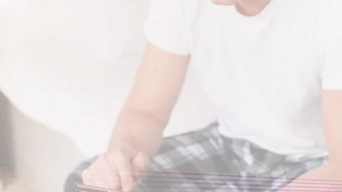 Mature man tapping phone on bed, camera pulling back, color lines sweeping, Stock Footage 333789997