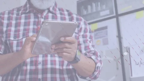 Mature man tapping tablet in office, camera widening revealing charts and sticky Stock Footage 333999047
