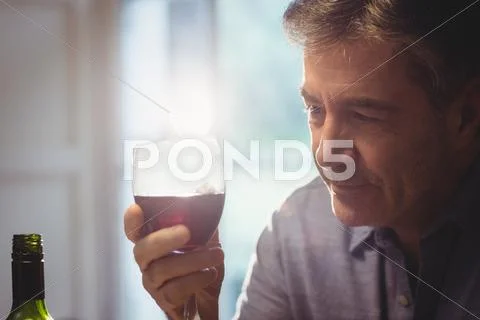 Mature man tasting red wine in his house Stock Photos