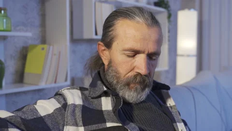 Mature man thoughtfully sitting on sofa at home. Stock Footage 227611051