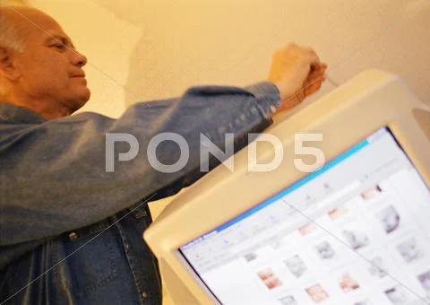 Mature Man Touching Wire At Back Of Computer