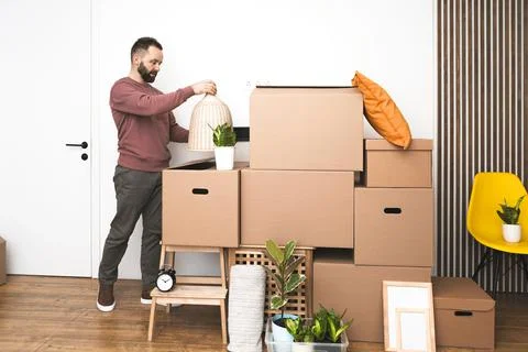 Mature man unpacking things from boxes while moving in new apartment. Stock Photos