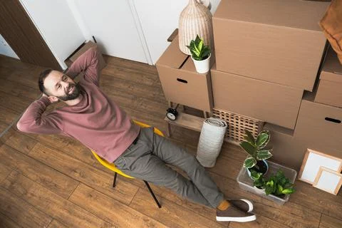 Mature man unpacking things from boxes while moving in new apartment. Stock Photos