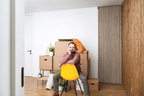 Mature man unpacking things from boxes while moving in new apartment. Stock Photos