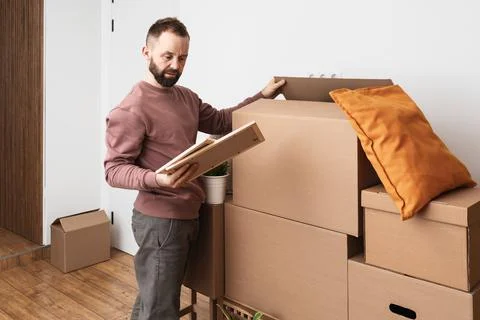 Mature man unpacking things from boxes while moving in new apartment. Stock Photos
