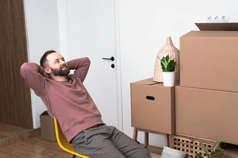 Mature man unpacking things from boxes while moving in new apartment. Stock Photos