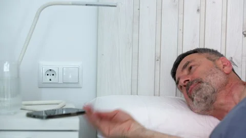 Mature man unplugging charger before going to sleep Vidéo 341580652