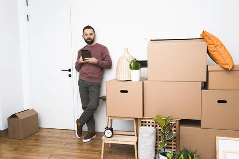 Mature man using his tablet while moving in new unfurnished apartment. Stock Photos