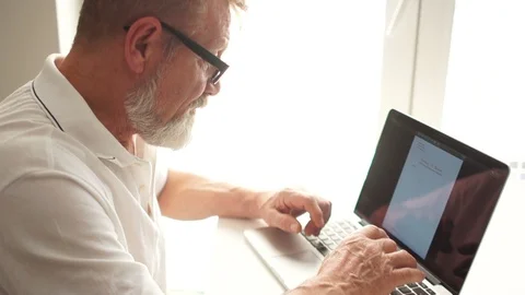 Mature man using a laptop to work at home. Writer or scientist at work. Senior Stock Footage 120791512
