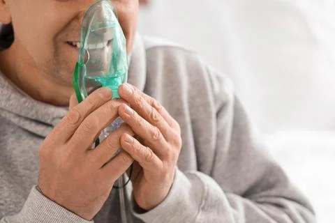 Mature man using nebulizer in bedroom, closeup Stock Photos