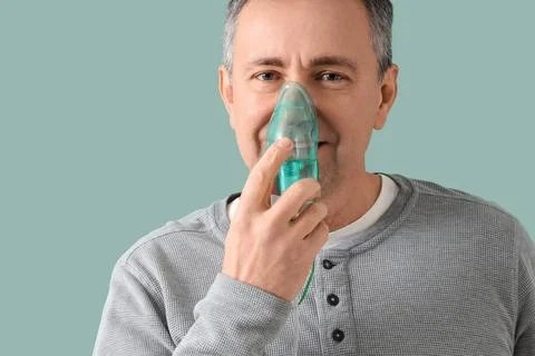 Mature man using nebulizer on green background, closeup Stock Photos