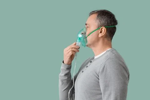 Mature man using nebulizer on green background Stock Photos
