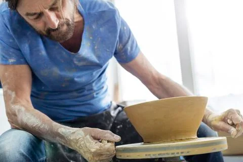 Mature man using pottery wheel in studio Stock Photos