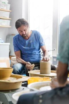 Mature man using pottery wheel in studio Stock Photos