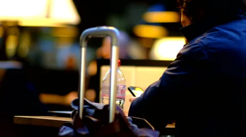 Mature man using smartphone and drinking water while sitting at the airport.  Vídeos de archivo 67827340