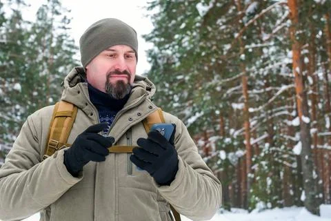 Mature man using smartphone for mobile navigation in snowy forest, winter t.. Stock Photos